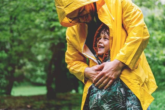 dad shelters child from rain with his coat